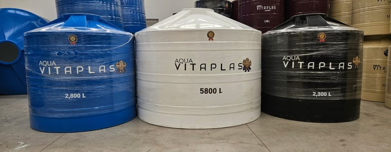 Three VITAPLAS water storage tanks in blue, white, and black, with capacity labels ranging from 2500L to 5800L, displayed in a warehouse setting