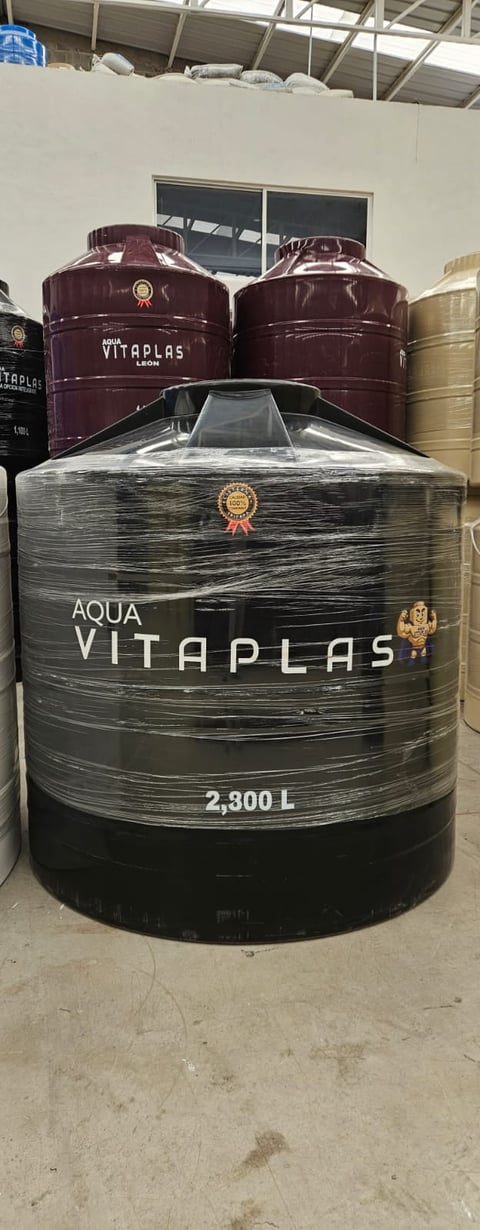 Large black cylindrical water storage tank labeled Aqua Vitaplas 2300L in an industrial warehouse setting with burgundy tanks behind it