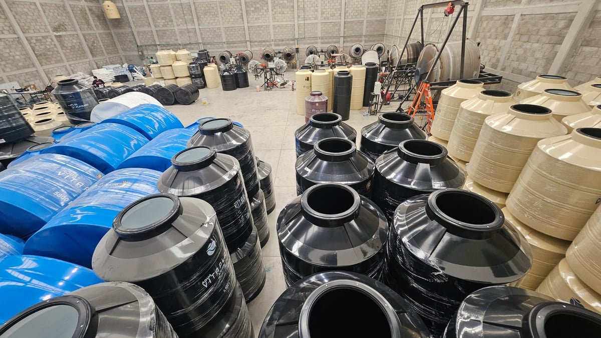 Industrial warehouse filled with rows of blue, black, and tan plastic drums and storage containers