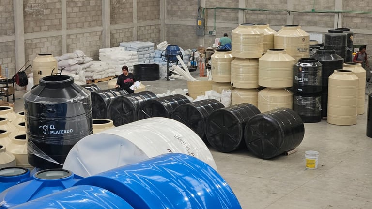 Industrial warehouse with stacked plastic drums, barrels, and containers of various sizes and colors arranged on concrete floor