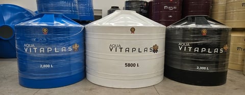 Three Vitaplas water storage tanks in blue, white, and black colors with capacity markings of 2,800L, 5,800L, and 2,000L respectively