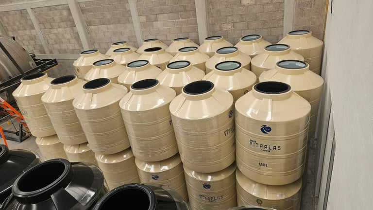 Multiple cream-colored cylindrical storage tanks or containers arranged in rows inside a room with white walls and tiled ceiling