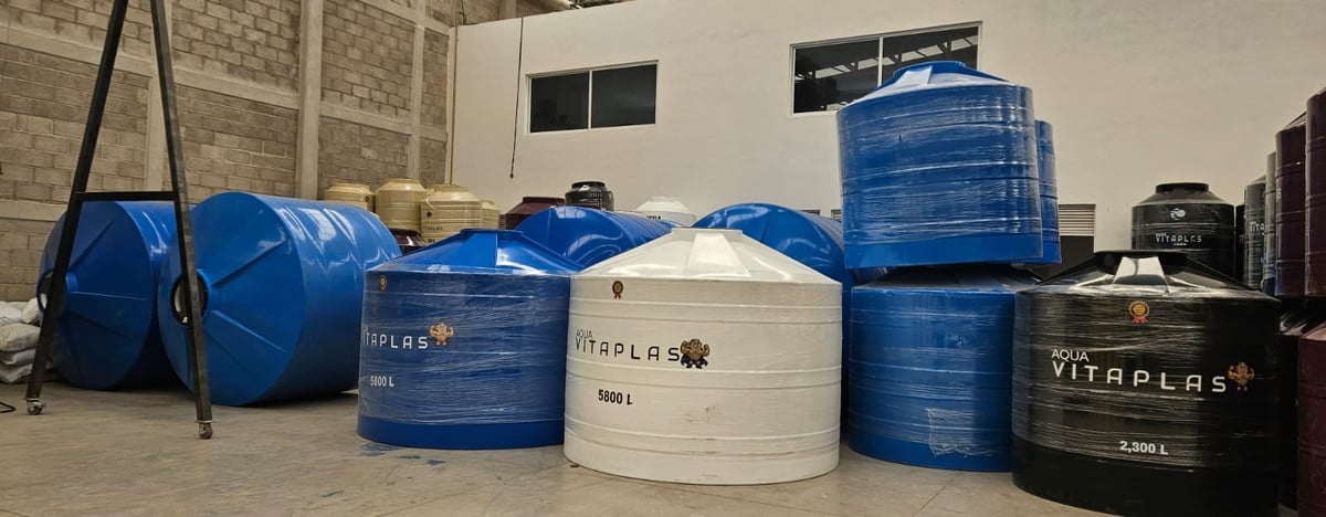 Storage tanks of various sizes in blue, white, and black displayed in an industrial warehouse setting